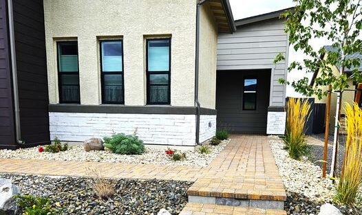Front entry way with new cobble style paver walkway, river rocks, larger rocks and DG. Xeriscape style with small shrubs and Northern Nevada native trees.